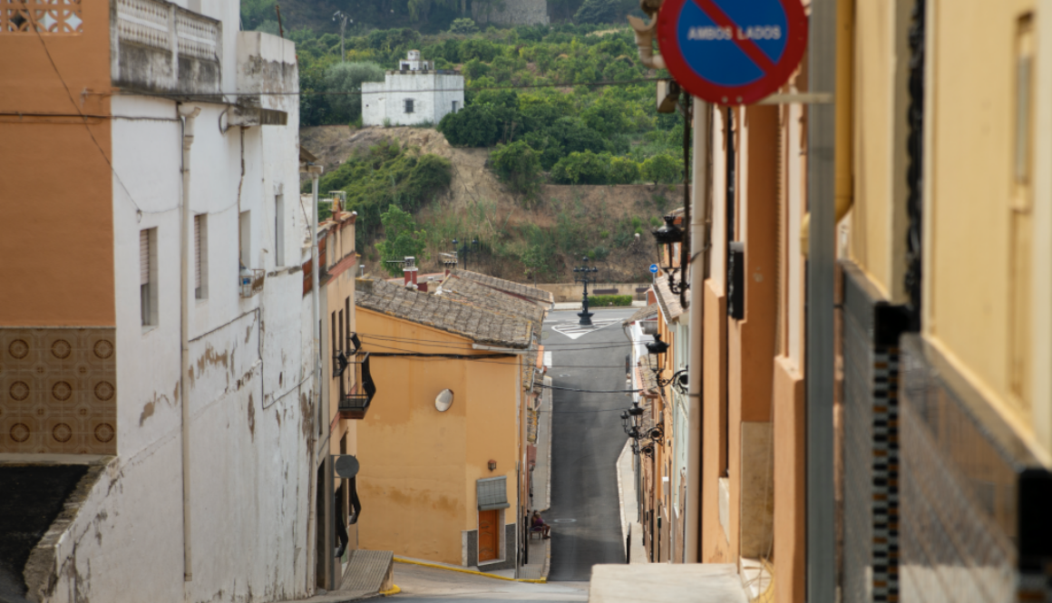 El carrer Major descendeix fins a arribar a l'exterior del poble. Al fons dalt, una casa blanca mitjana envoltada de fruiteres.