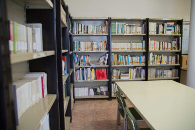 Detall de les prestatgeries amb llibres, taules i cadires de la biblioteca pública municipal de Sellent.