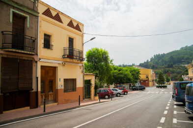 Part de l'avinguda País Valencià, carretera principal que travessa el poble, amb alguns cotxes aparcats.